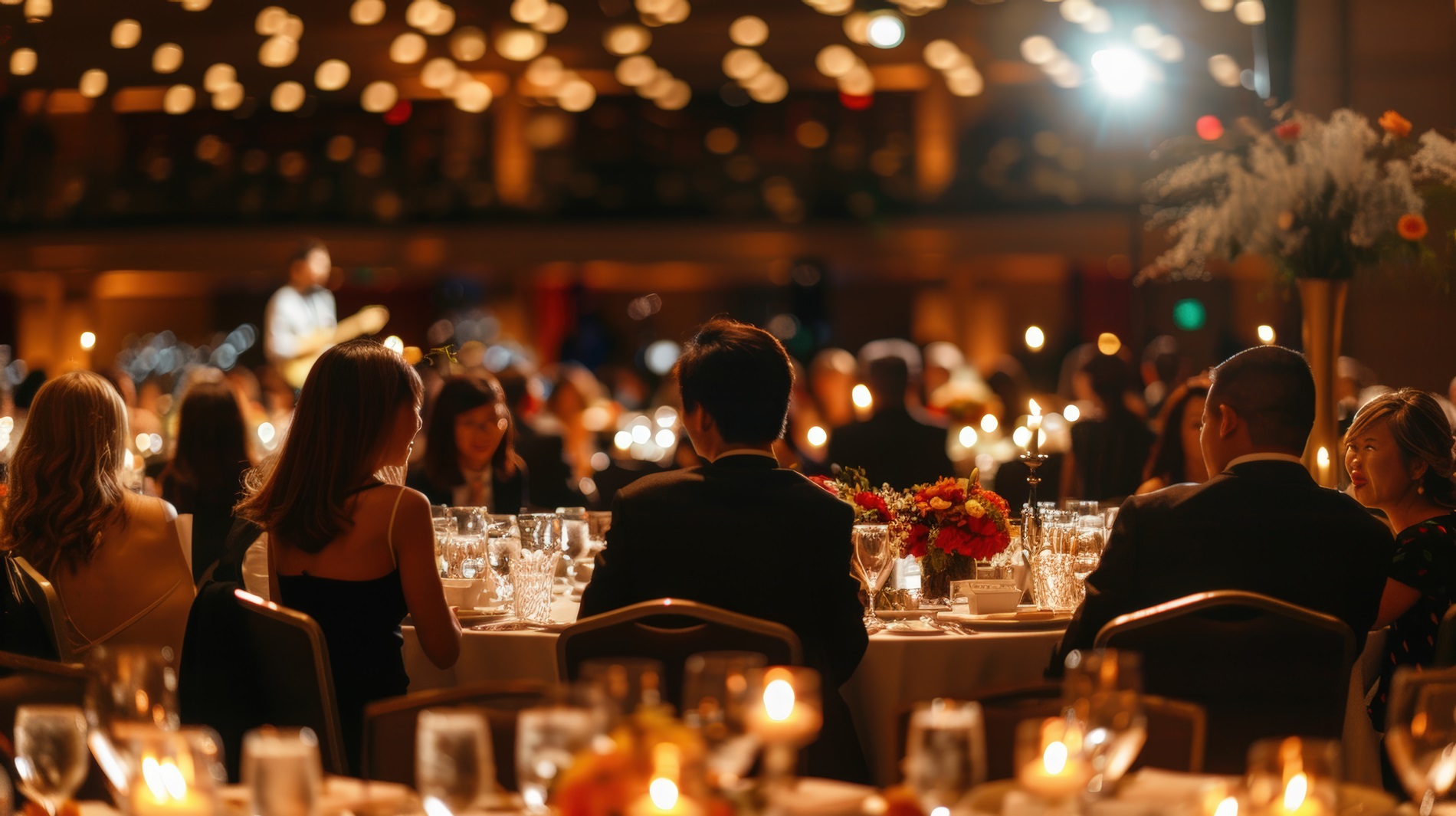 gut gekleidete Menschen bei einer Abendveranstaltung an einem schön gedeckten Tisch bei gedämpftem Licht